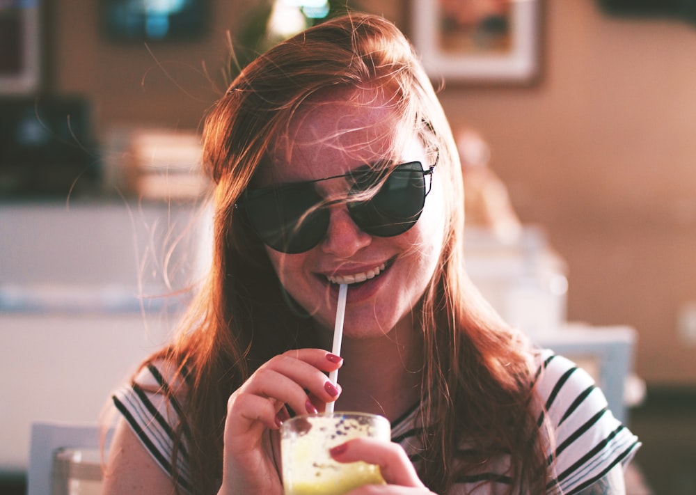 woman sipping drink while smiling