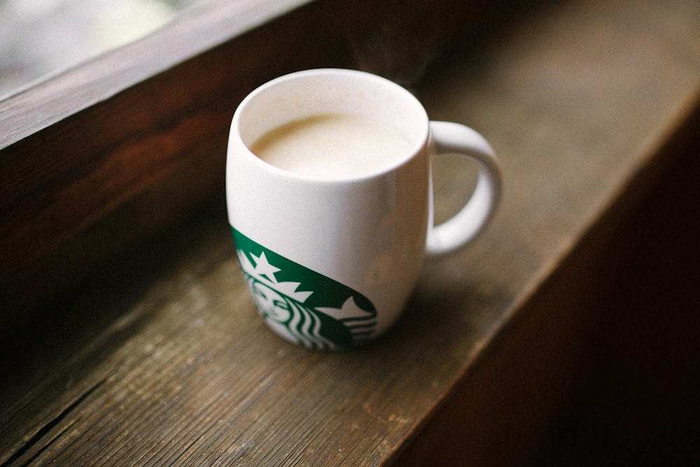 Foto eines weißen Starbucks-Bechers auf brauner Holzoberfläche