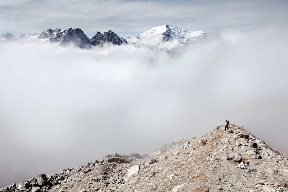 Persona che si leva in piedi sulla parte anteriore del picco delle nuvole bianche e della montagna ghiacciata