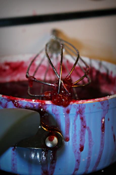 Hands stirring a pot of simmering jam over a traditional stove.