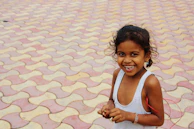 A smiling child wearing a bright yellow shirt, holding a puzzle piece shaped like a star.
