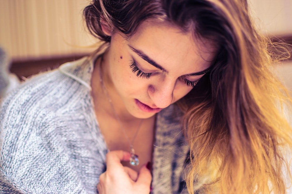 woman looking down while holding necklace pendant