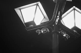 A black and white photo of a vintage street lamp casting soft shadows on a cobblestone street.