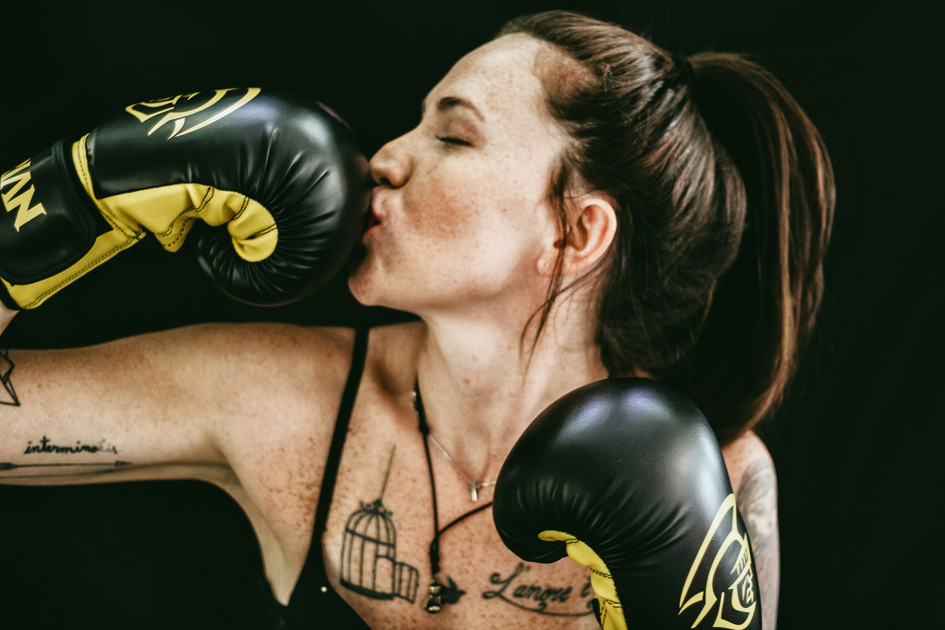 woman kissing black leather boxing gloves