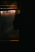 Silhouette of a person framed by soft illuminated window panes.