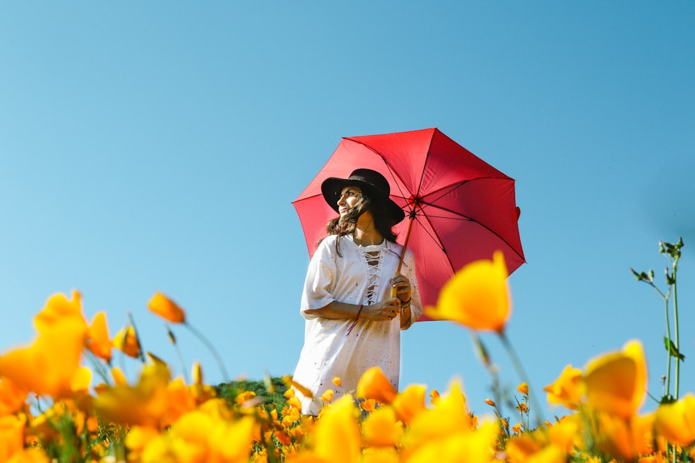 Mujer en vestido blanco bajo paraguas rojo