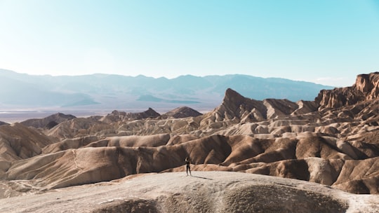 person standing on top of brown hill in Death Valley National Park, Zabriskie Point United States