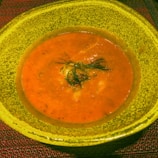 A close-up of a steaming bowl of creamy tomato soup.
