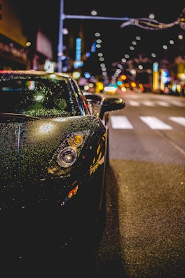 Sleek black premium car parked under city lights at night.