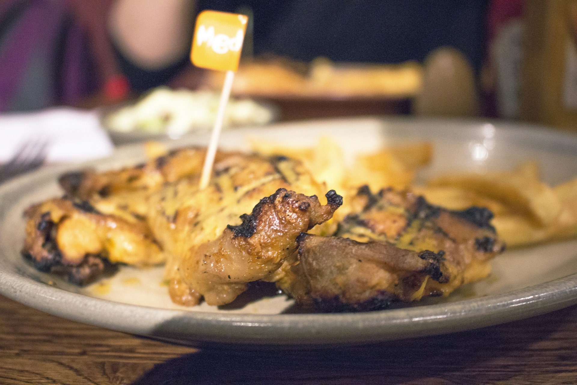 Grilled chicken breast served with golden french fries and a fresh, vibrant salad in a cozy restaurant setting.
