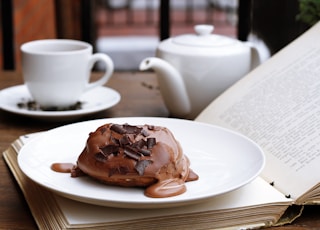 Chocolate dessert on an open book with a tea pot and tea cup in the background