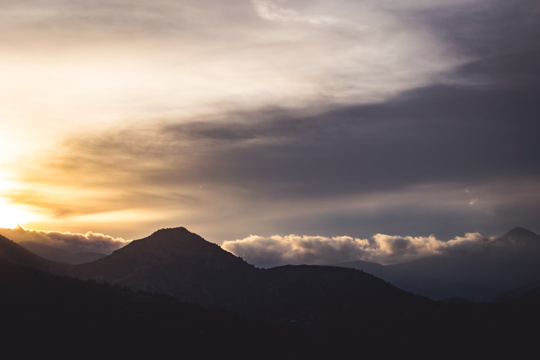 silhouette of mountain under cloudy sky at golden hour\