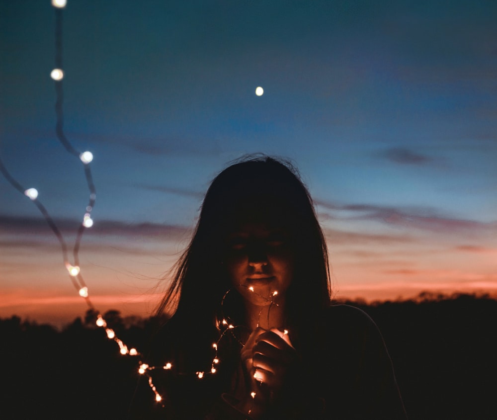 woman holding gold string lights