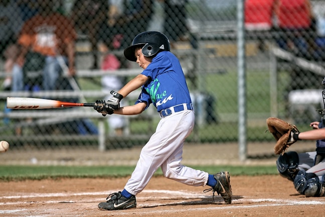 A smiling player receiving individual lesson tips from a mentor, with a backdrop of baseball gear and a bible.