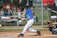 A young baseball player practicing batting swing with a coach guiding closely.