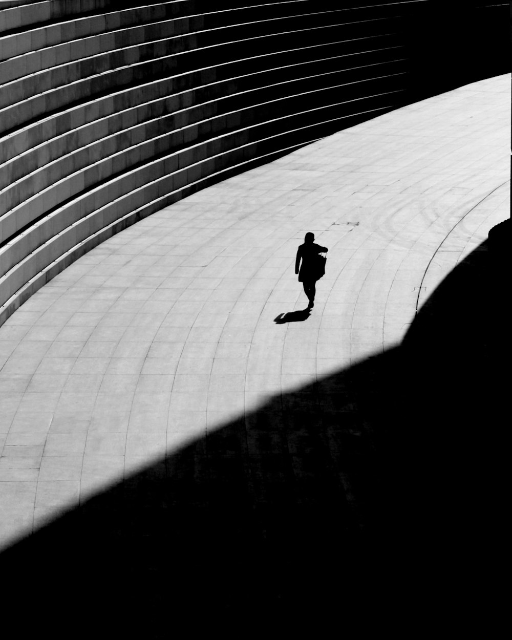 silhouette di una persona che cammina sul pavimento di cemento grigio