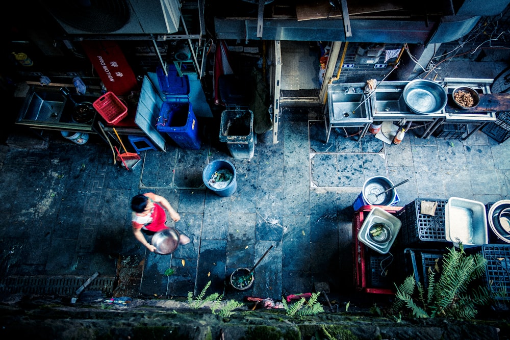 top-view photo of person holding container near blue trash bin