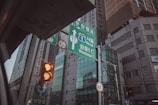 A street scene in an urban area with a focus on road signs and traffic lights. The road signs provide directions to Seoul and Wondong IC, and there are traffic lights showing amber lights. Tall modern buildings and glass windows form the backdrop. Additionally, wires and poles are visible, contributing to the cityscape.