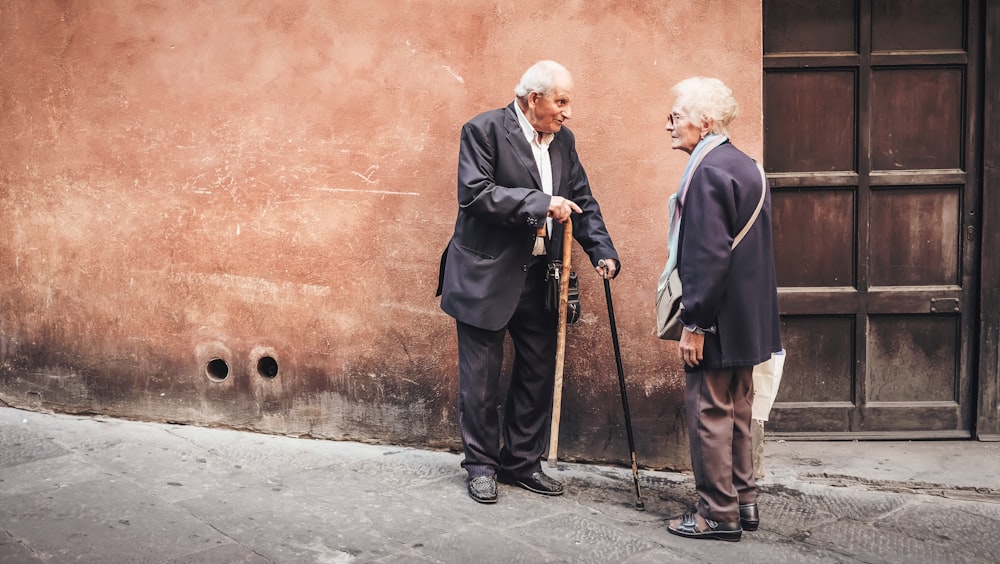 An old man and woman having a conversation with their canes next to a doorway.