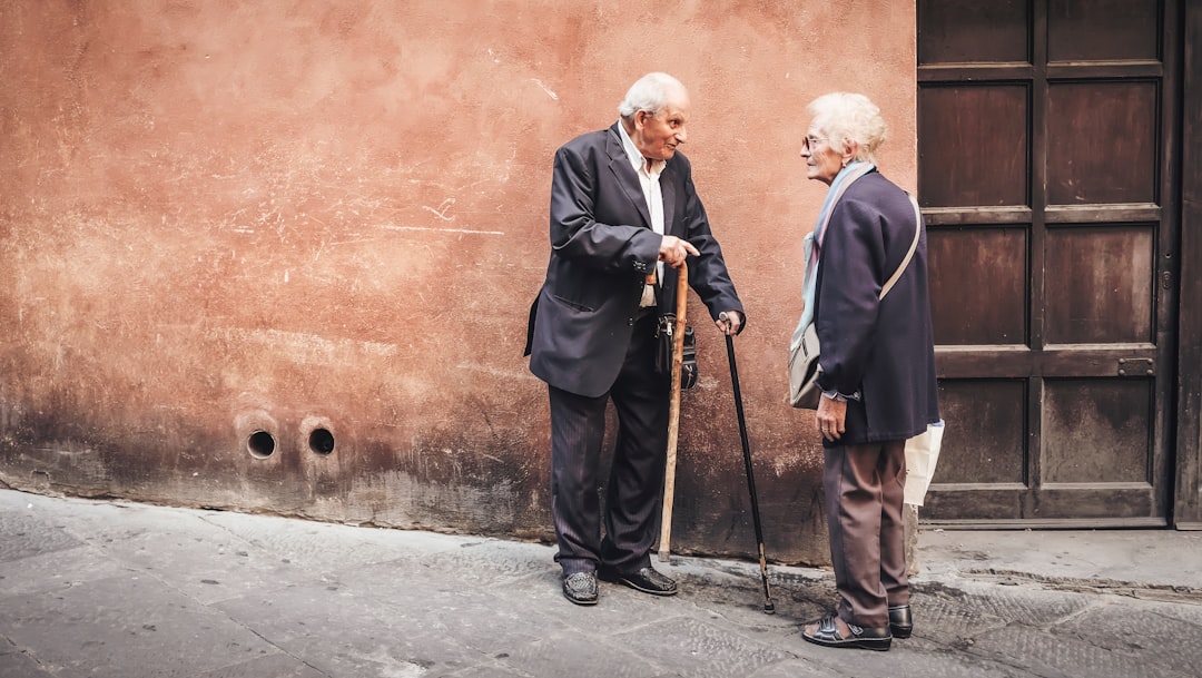 two person talking while standing near wall, old people conversing