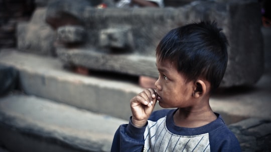boy holding his lip standing on sidewalk in Angkor Wat Cambodia