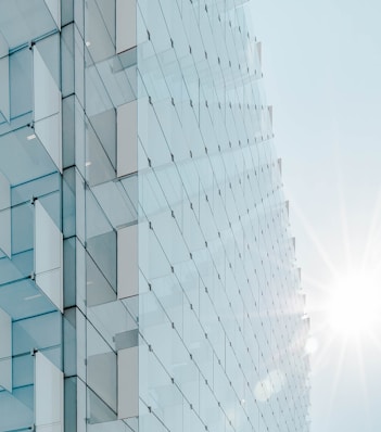 glass panel high-rise building under blue sky with sun raise