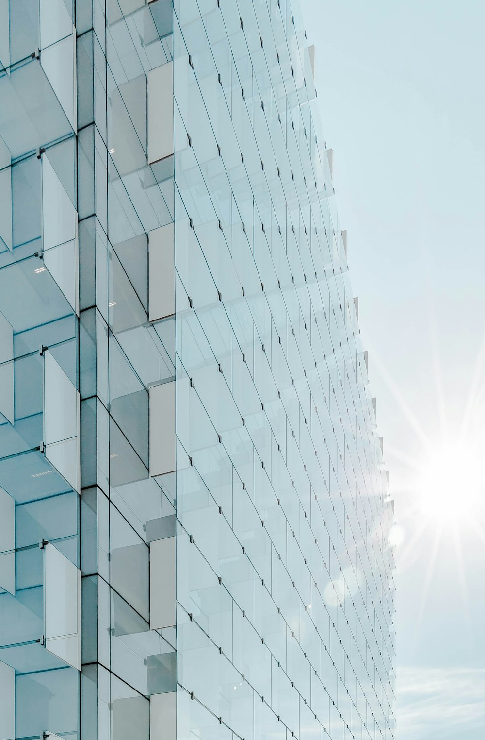 glass panel high-rise building under blue sky with sun raise