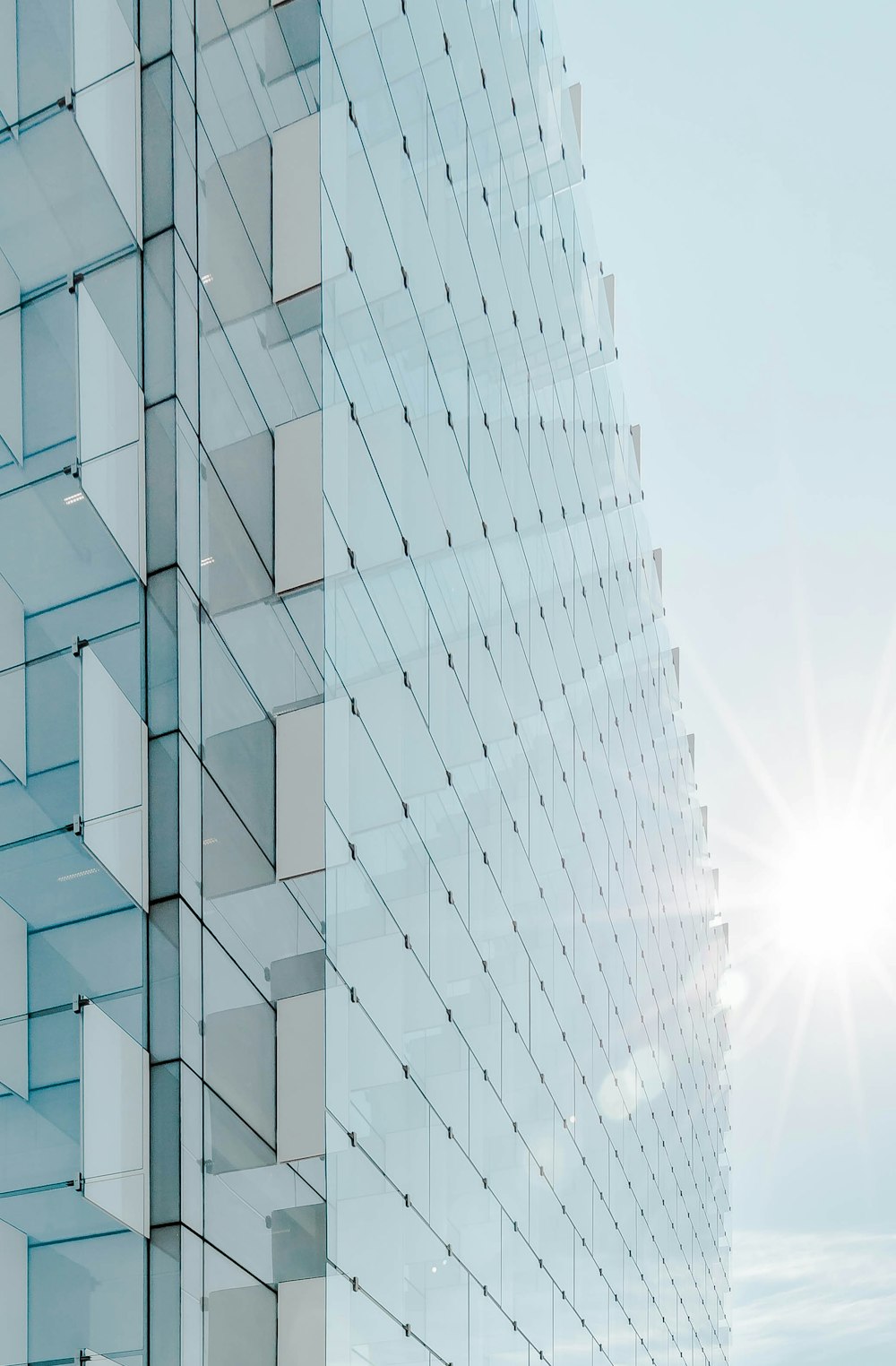 Edificio de gran altura con panel de vidrio bajo cielo azul con salida del sol