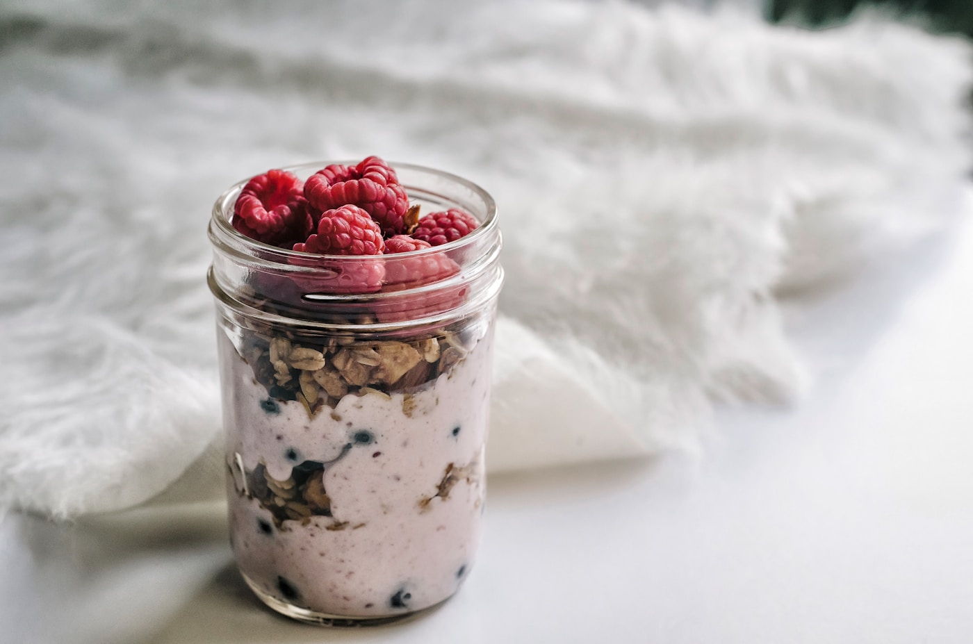Creamy overnight oats in a mason jar with fresh berries and honey