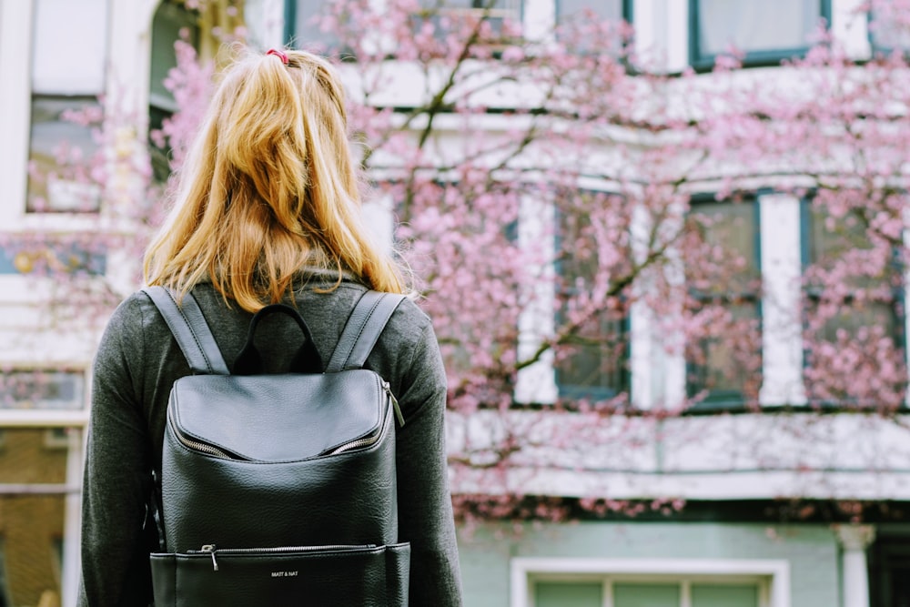 woman wearing backpack facing concrete building