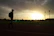 Close-up of a fan proudly wearing the élite t-shirt, standing against a backdrop of a running track at sunset.