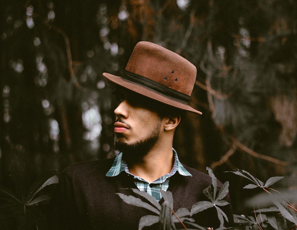 homme portant un chapeau brun debout devant l’arbre