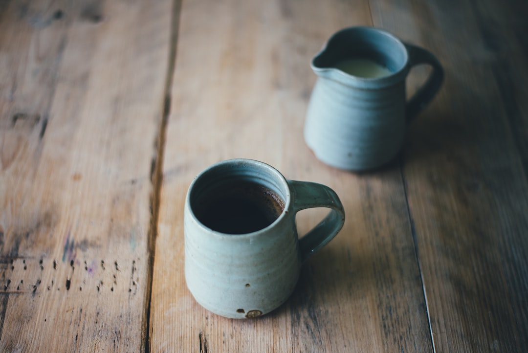 white ceramic mug with brown and white liquid inside on brown wooden surface, My first cup of coffee in my new Leach Pottery ware <em></figure>eee</em>
