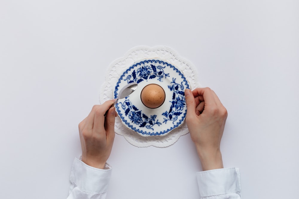 man holding white and blue caucer