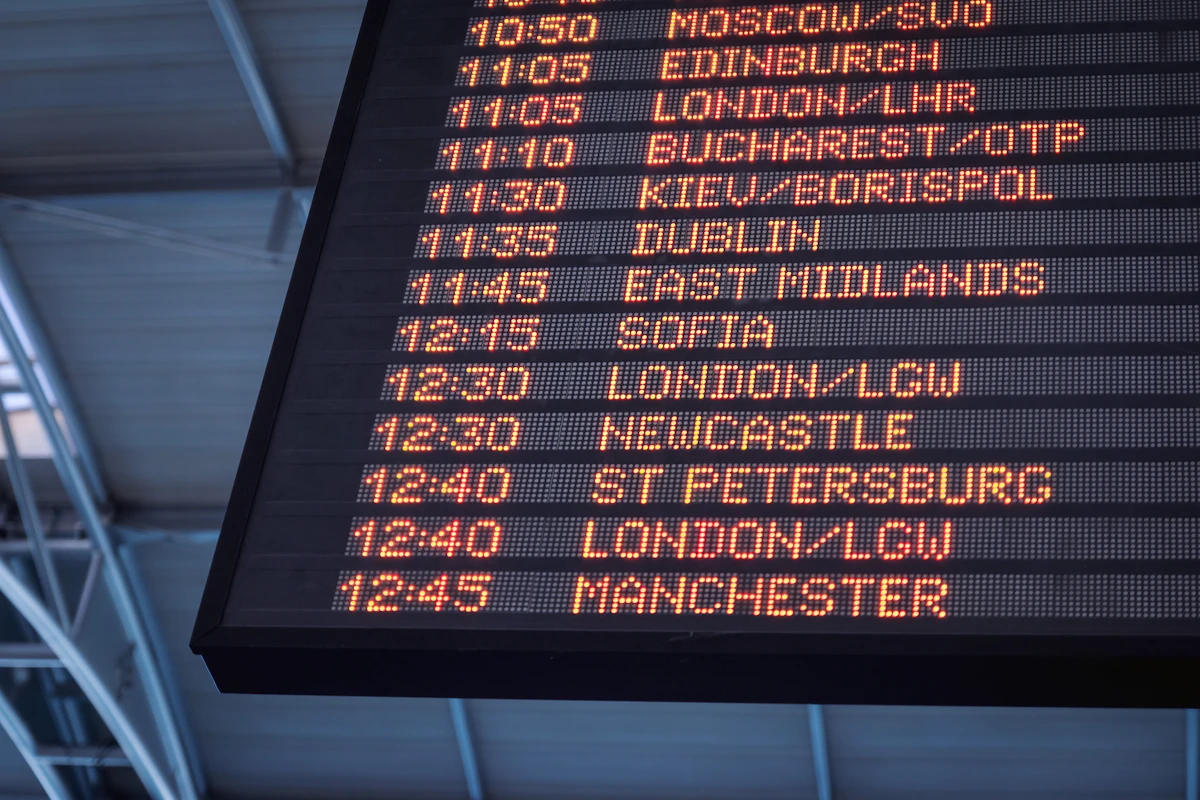 An airport departure board showing rows of flight listings