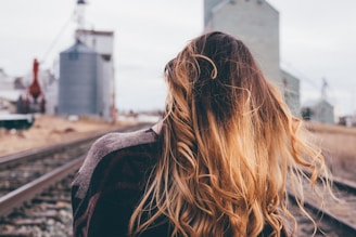shallow focus photography of woman standing on train rail