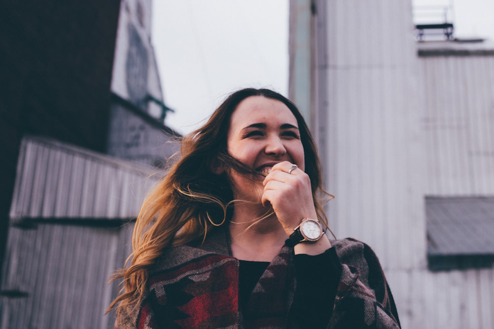 woman standing while laughing and biting her finger