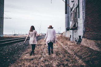 photo of two persons walking along railway