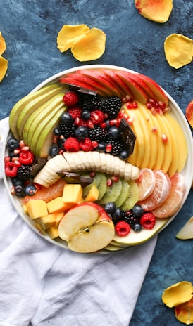 bowl of sliced fruits on white textile