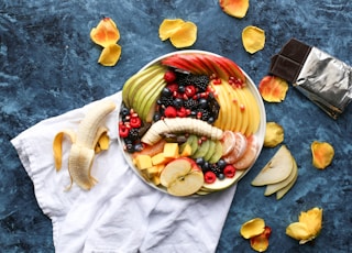 bowl of sliced fruits on white textile