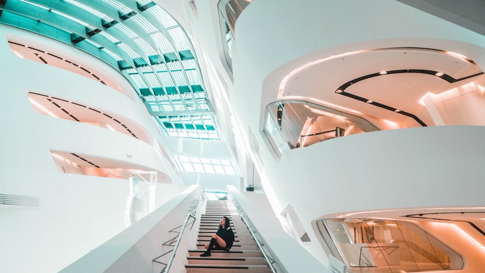 sitting woman on stairs inside white concrete building