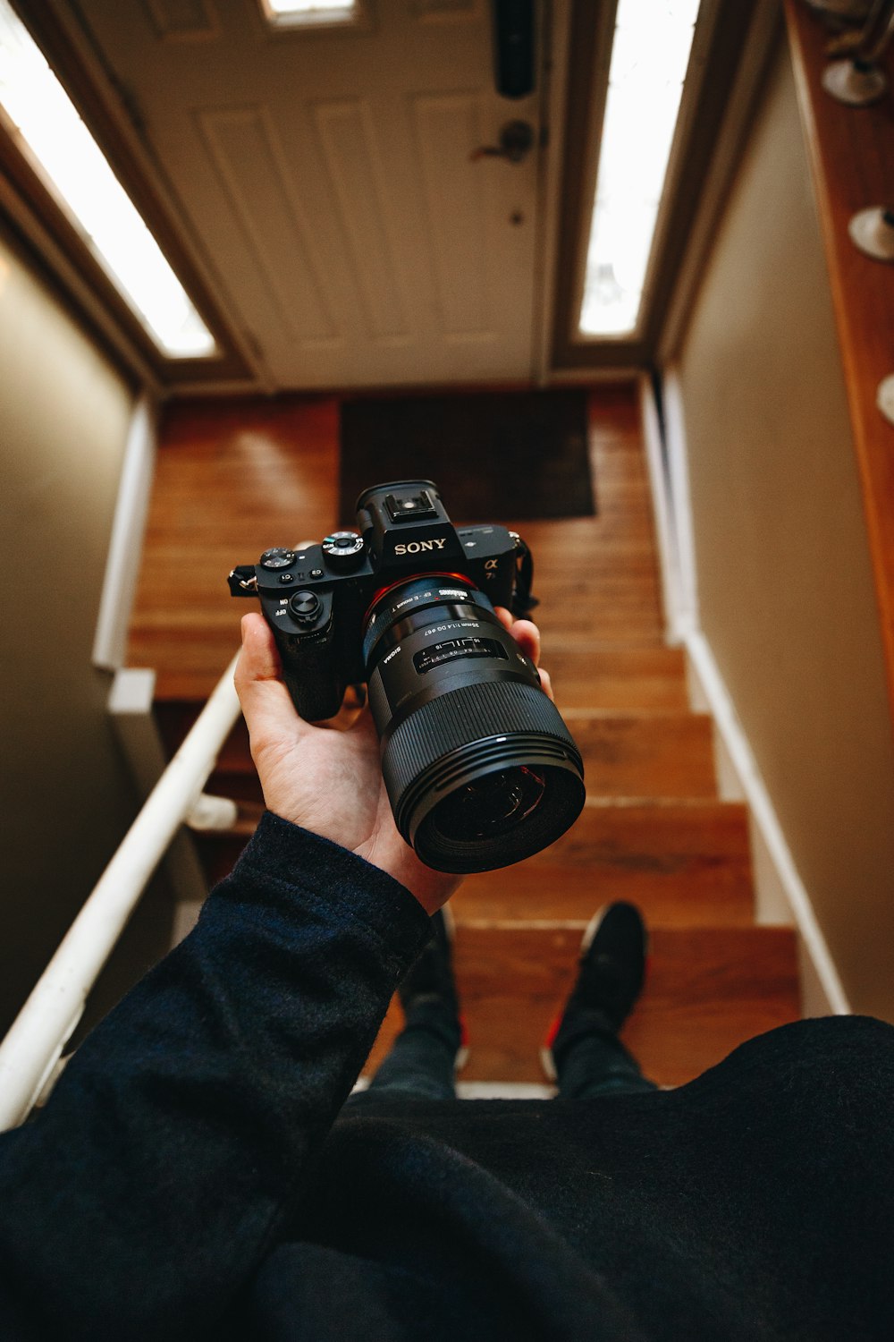 persona sosteniendo una cámara Sony DSLR negra en la escalera