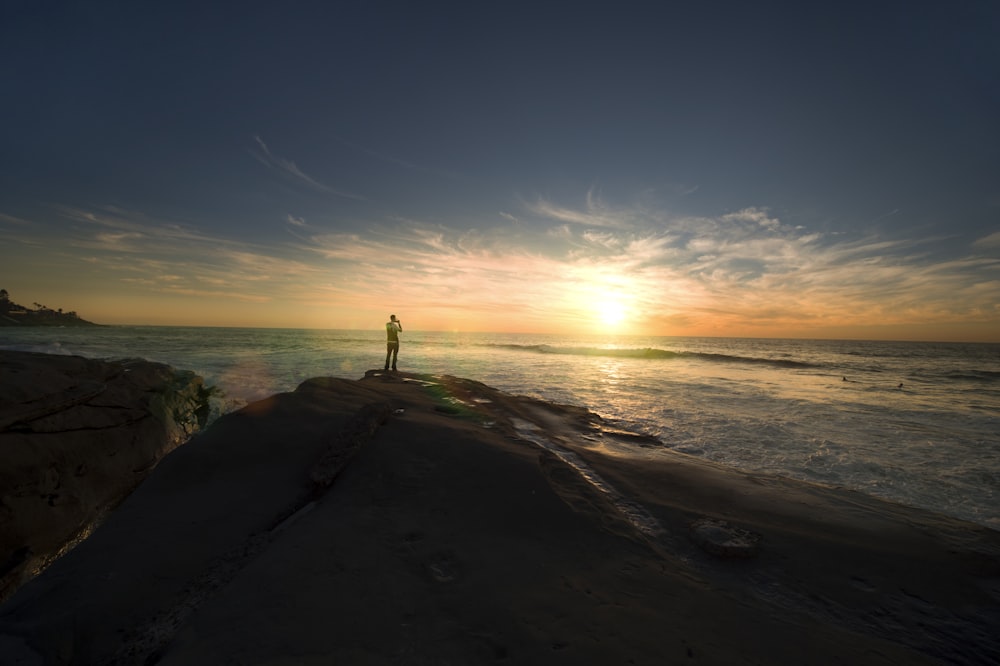 person standing on mountain facing sun at golden hour