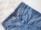 A pair of blue denim jeans with a visible brand tag on the waistband, placed on a white, fluffy surface.