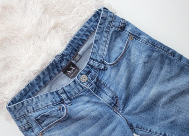 A pair of sleek men's blue denim jeans on a wooden surface.