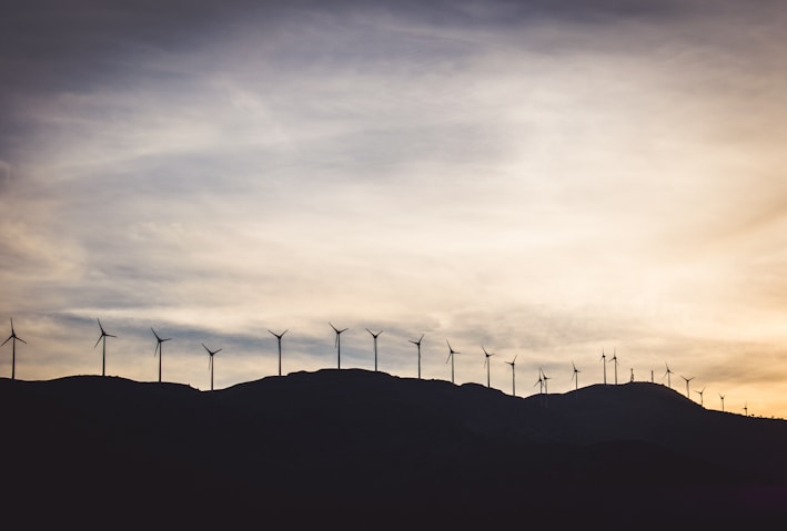 silhouette photo of wind turbines on hill