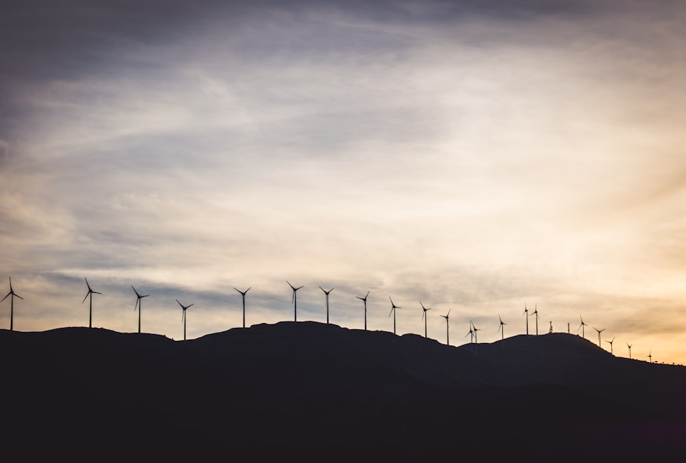 Silhouettenfoto von Windkraftanlagen auf dem Hügel