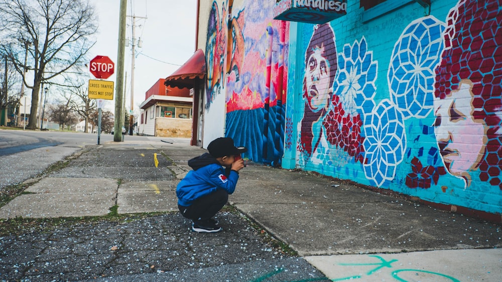 boy wearing blue hoodie in front of wall with artworks