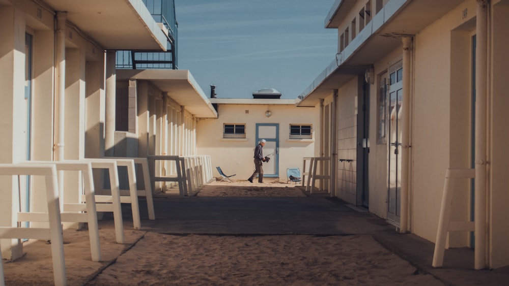 man walking between white buildings during daytime