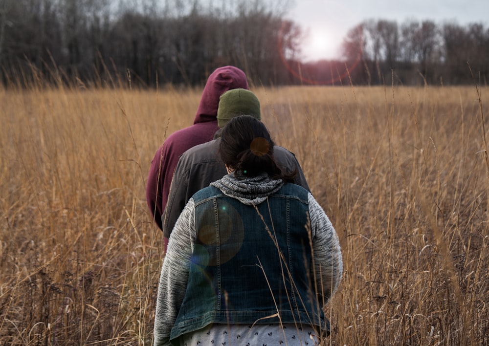 three person walking on brown field during daytime